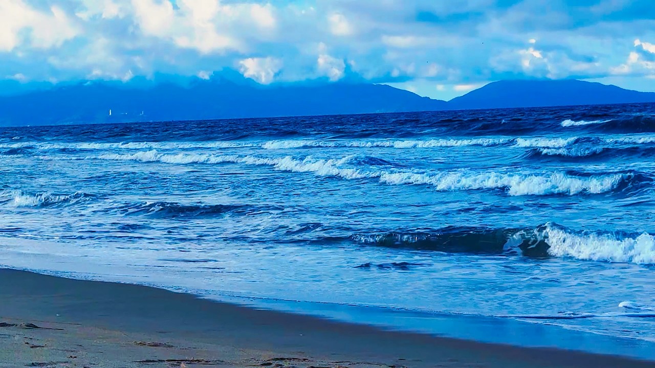 Peaceful Ocean Waves on Sandy Beach with Mountains in Distance