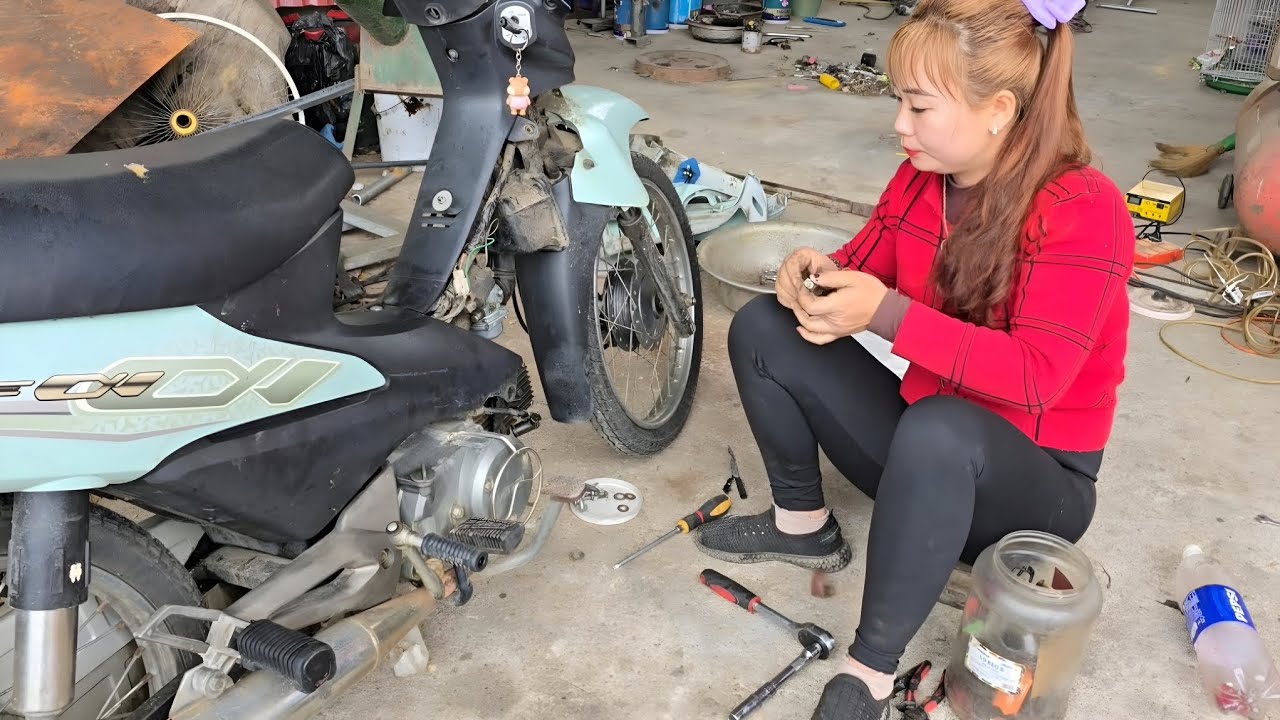 The girl repairs and restores a neighbor's motorbike.
