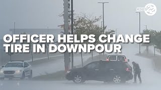 Police officer helps change tire during storms and heavy downpour