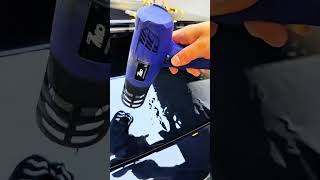 Blue heat gun smoothing car vinyl wrap surface