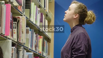 Woman In Library Browsing Through Books