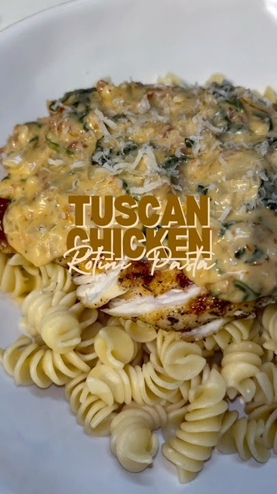 Creamy Tuscan Chicken Topped on a Bed of Rotini Pasta.