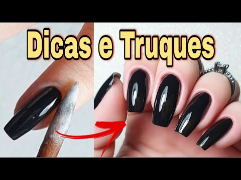 Detalhe das mãos de uma manicure pintando as unhas com um desenho de  esmalte preto