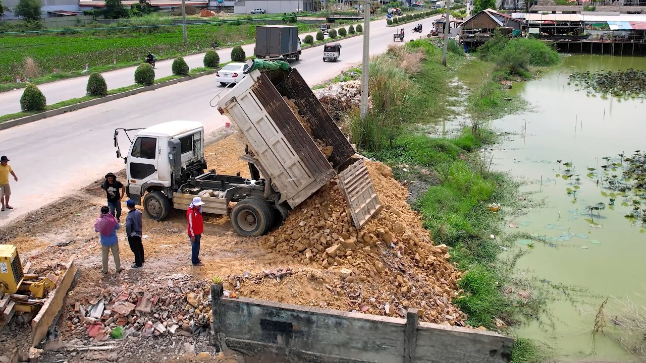 Start a new big project, show the landfill By Bulldozer Komatsu D31p pushing the soil into the pond.