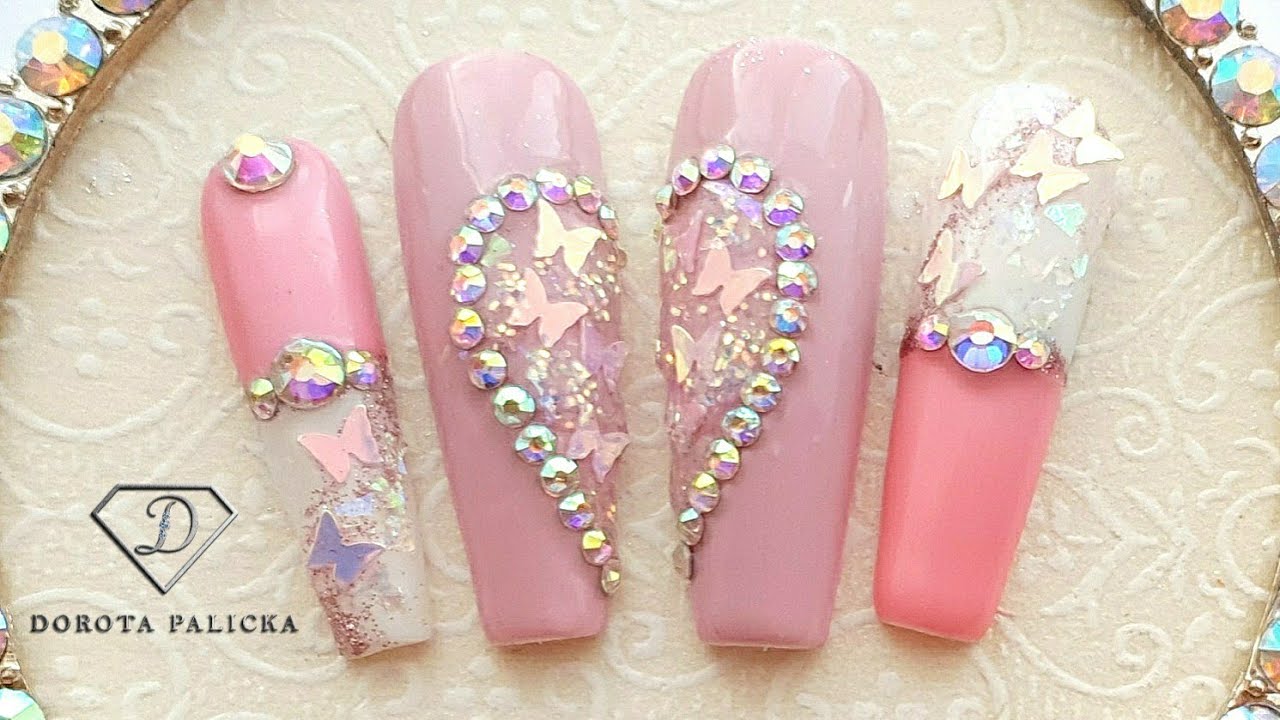 Crystal heart nail art with butterfly and glitter encapsulation.