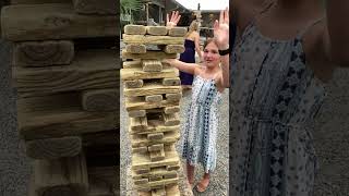 Girl pulls out oversized Jenga piece then places it on top and it falls on her head (Slow motion)