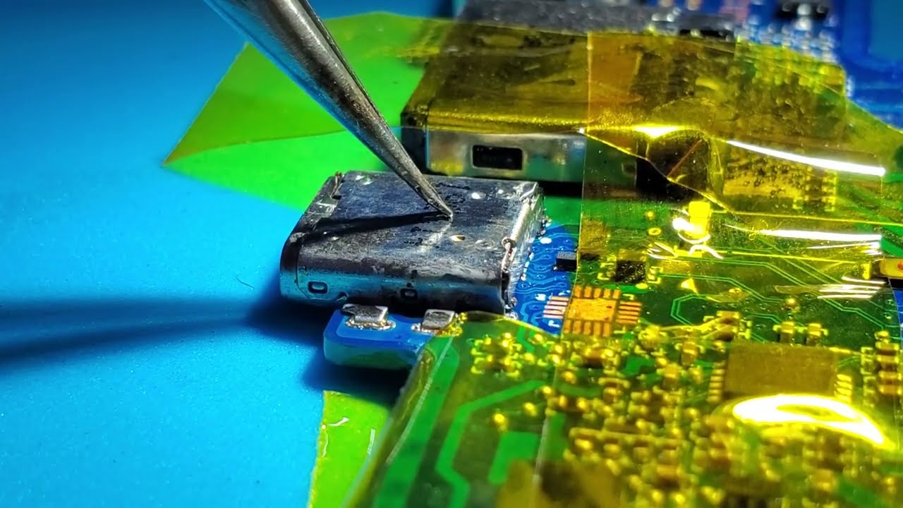 Soldering new USB-C connector on laptop motherboard using hot air station to fix charging issue.