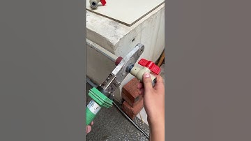 Part 3 person using a green pipe wrench to adjust a white water valve that has a red handle