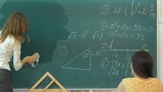 Female Teacher At High School Washes The Chalkboard And Lookng To The People In Class | Stock Female Teacher At High School Washes The Chalkboard And Lookng To The People In Class | Stock