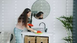 Cute housewife washing bathroom sink and dancing enjoying housework at home