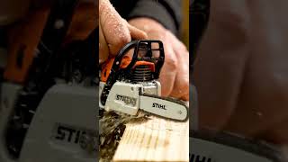 A close-up cinematic shot captures a miniature chainsaw cutting through a wooden plank.