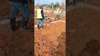 Workers Using a Vibratory Rammer to Compact Soil on an Early-Stage Construction Site