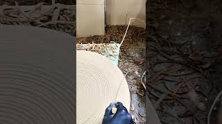 Cutting circular clay piece with wire tool on pottery wheel