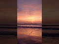 A short cinematic video of a beautiful sunset at the beach, waves moving slowly, peaceful mood