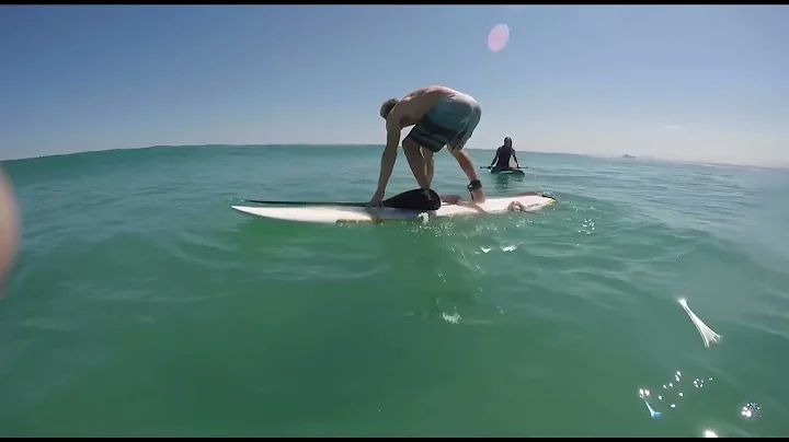 Giant squid attacks a man on a surfboard.