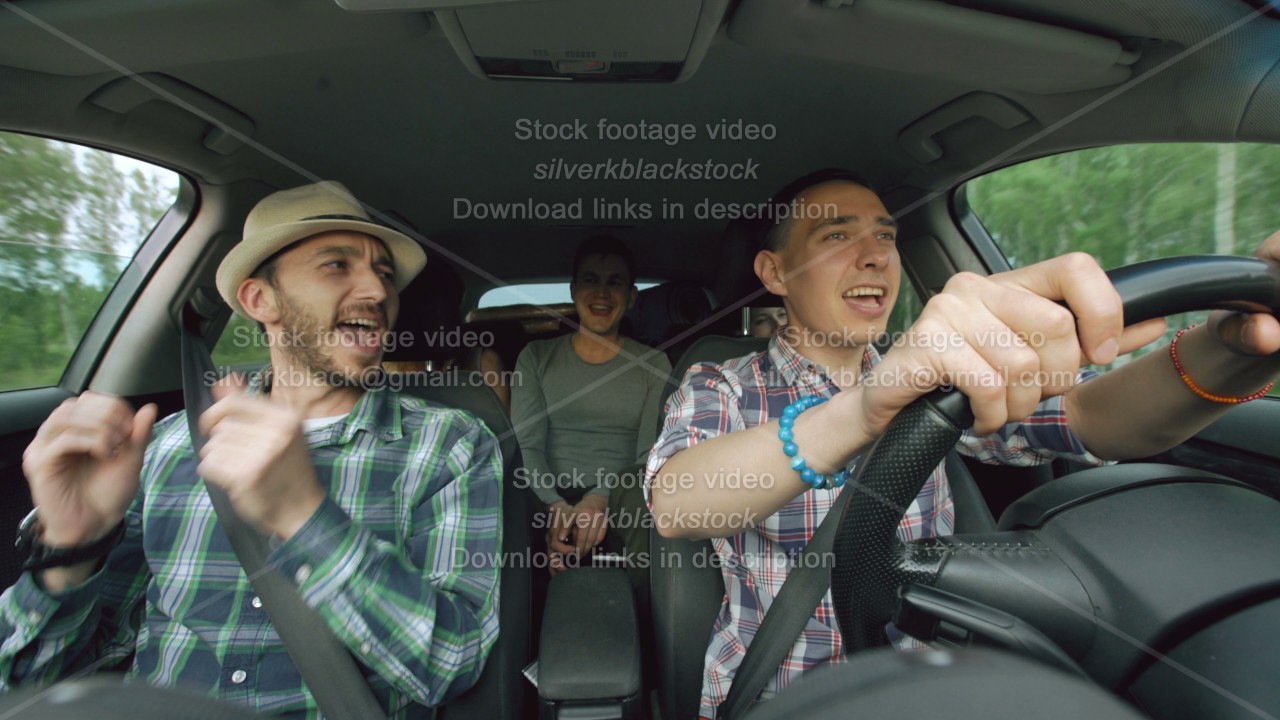 Group of happy friends in car singing and dancing while drive road trip ...