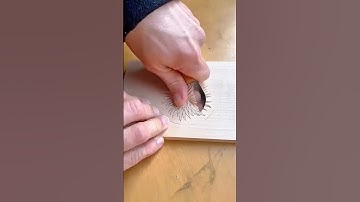 Hand-carving a detailed floral pattern on wood using a curved gouge for precise shaping