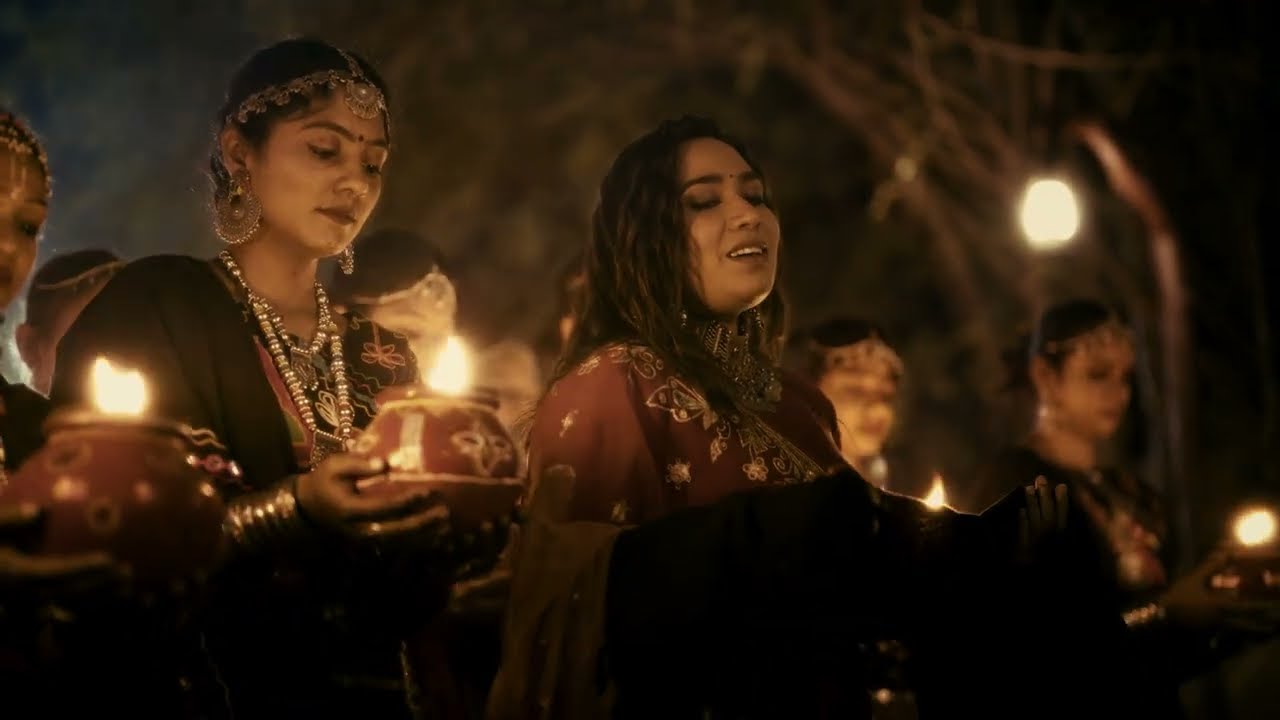 Ishani Dave holding a diya among garba dancers, in a still from the Bheliyo video