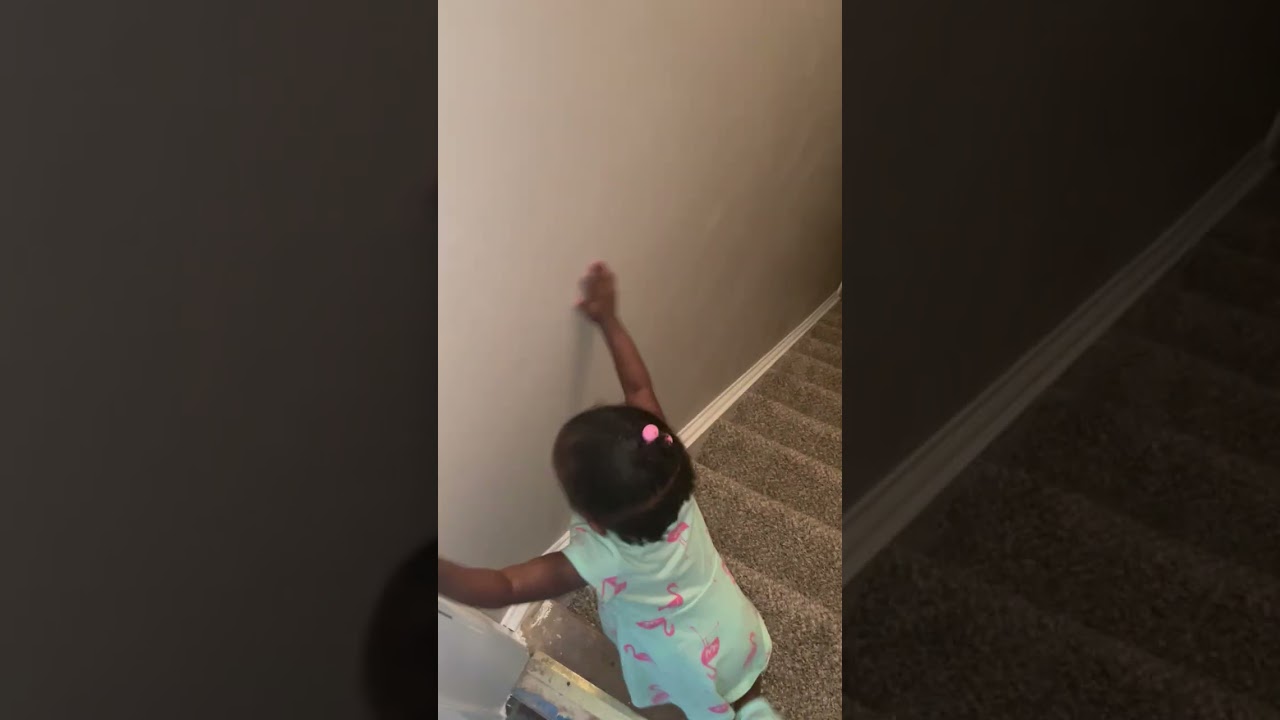 Little girl holds onto wall then falls down the stairs
