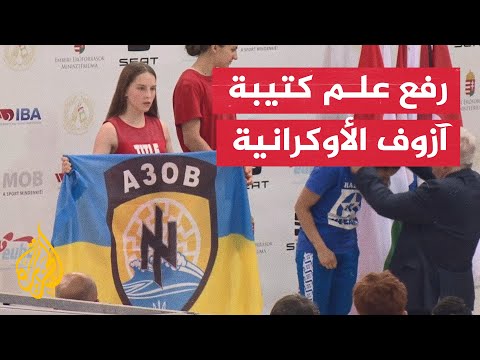 فتاة أوكرانية ترفع علم "كتيبة آزوف" خلال حفل بطولة الملاكمة في المجر
