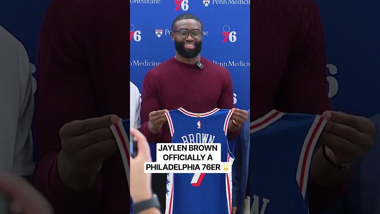 Jaylen Brown holds up his #7 Sixers jersey for the first time