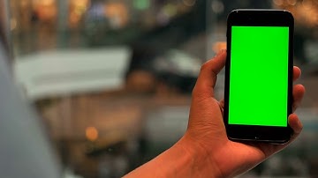 close up shot of man hands holding the cell phone with green screen on escalators at stylish modern
