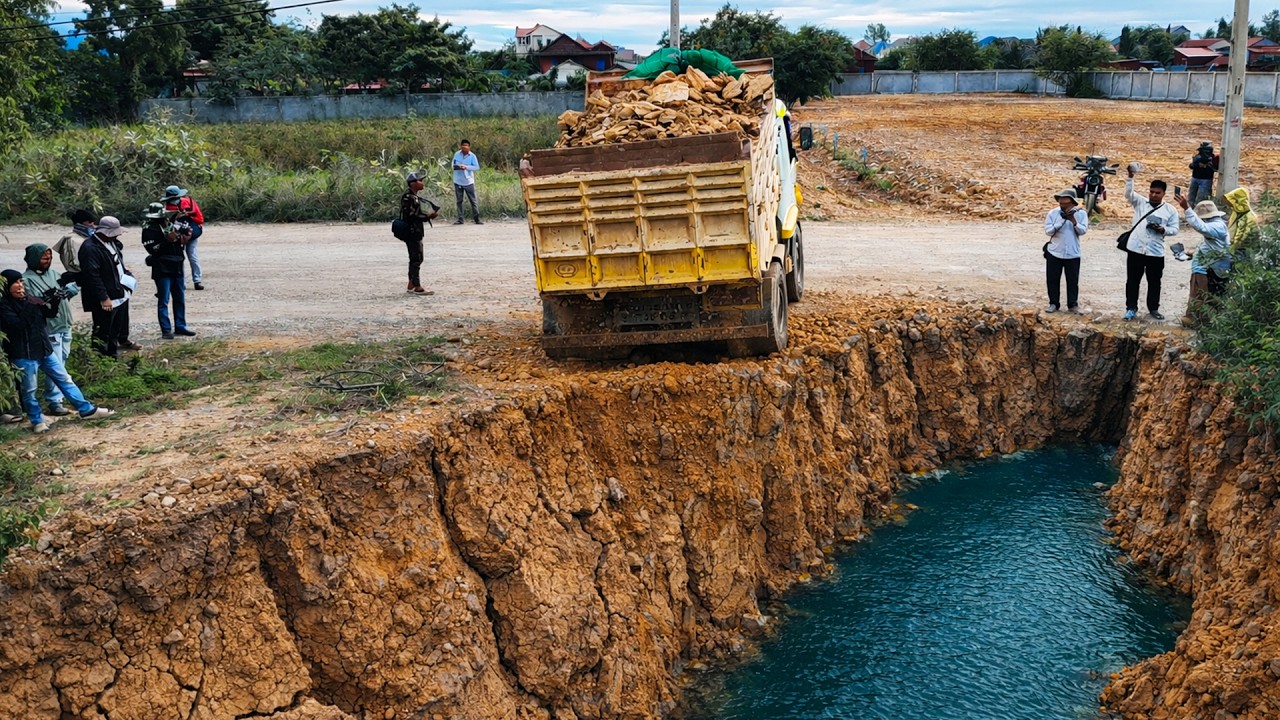 Nice work bulldozer operator filling land with soil with dump trucks 