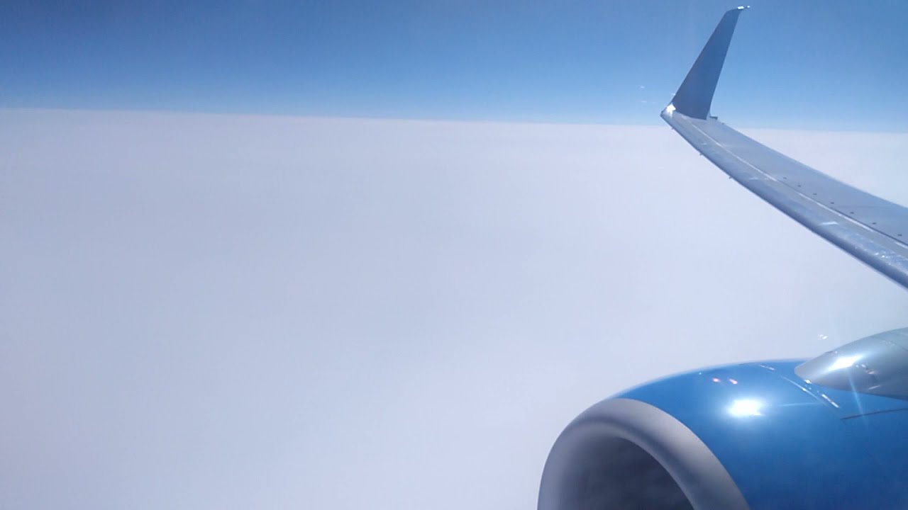 Вид из окна (иллюминатора) самолета на горы и облака