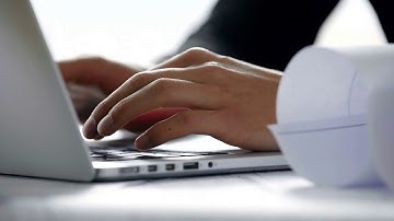 close up of young architect hands typing on laptop computer keyboard in white modern office in