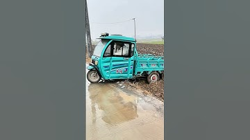 The electric tricycle drives out of the muddy field and onto the cement road