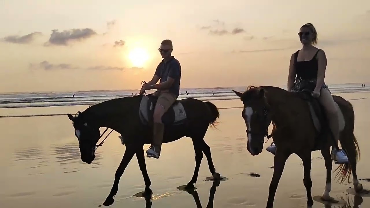 beautifull couple riding at mesari stables in bali at seminyak beach with wonderful sunset
