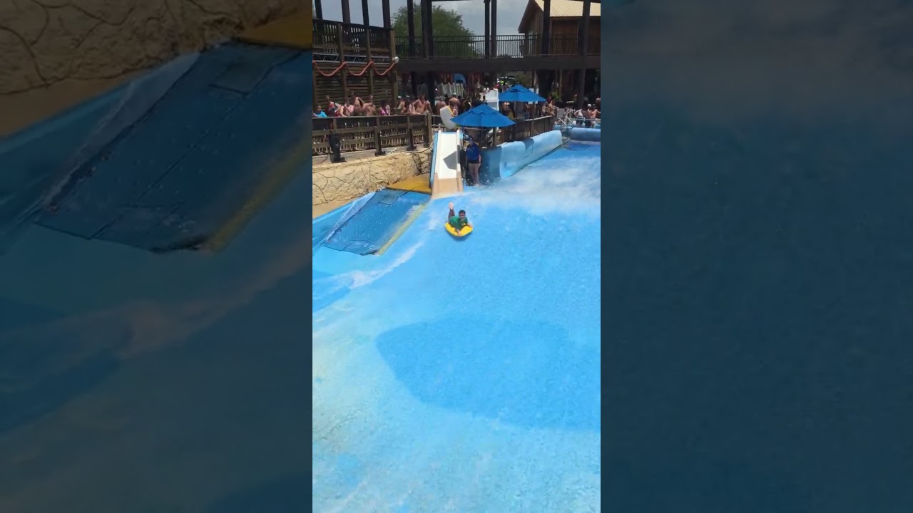 Boy rides boogie board down slide into wave pool/FlowRider and takes a tumble