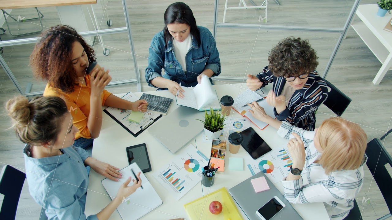 Ambitious women talking doing high-five clapping hands sitting at table in office