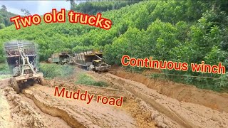 Two old trucks hold hands through the mud