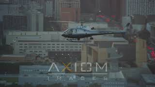 Track an LAPD helicopter flying by Downtown Los Angeles, California at sunset | AX0162_095