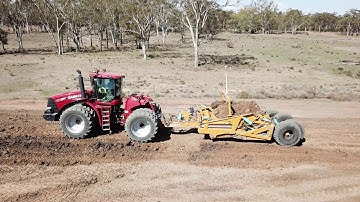 TOOMEY 4000B Scraper behind an STX450 unloading clay onto a water storage wall.