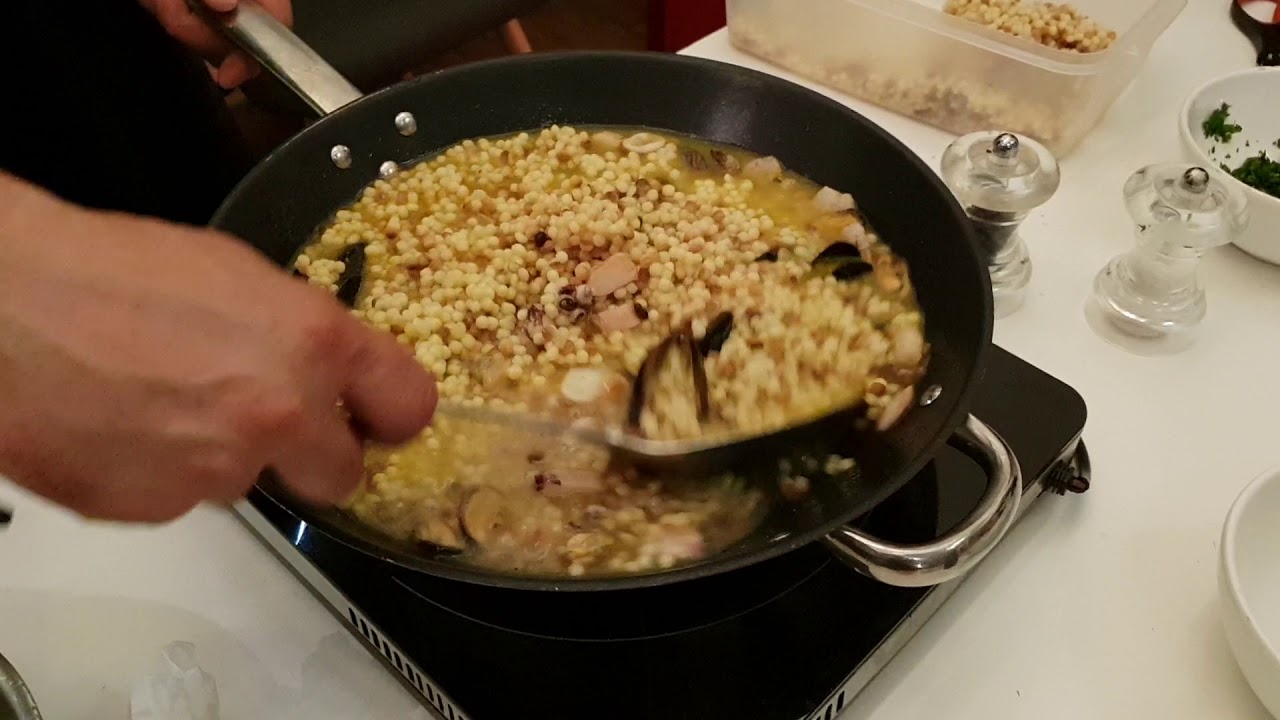 Сардинийская традиционная паста fregola с морепродуктами в процессе приготовления.