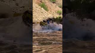 Paddle boat going through a medium sized rapid.