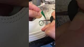 Painting a linked rings and hearts design onto leather converse wedding trainers 