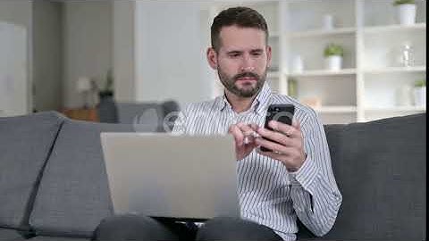 Focused Man Working on Smartphone and Laptop at Home | Stock Footage - Envato elements