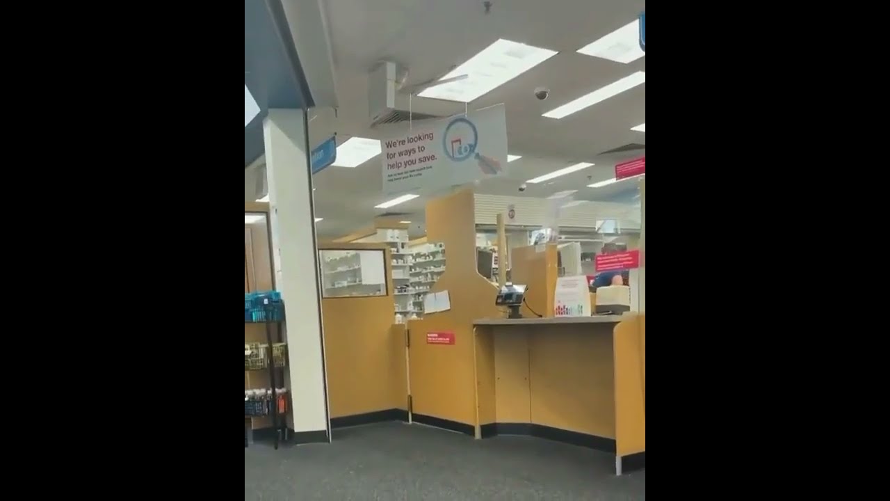 A man walks behind the CVS pharmacy counter & grabs prescription medication
