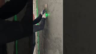 meplester permukaan dinding beton menggunakan alat cetok manual dipandu cahaya laser level hijau