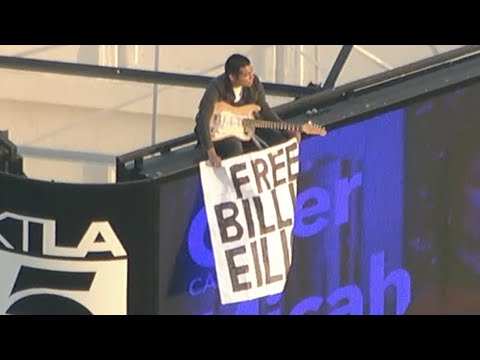 Man climbs KTLA tower in Hollywood holding "Free Billie Eilish" sign and electric guitar