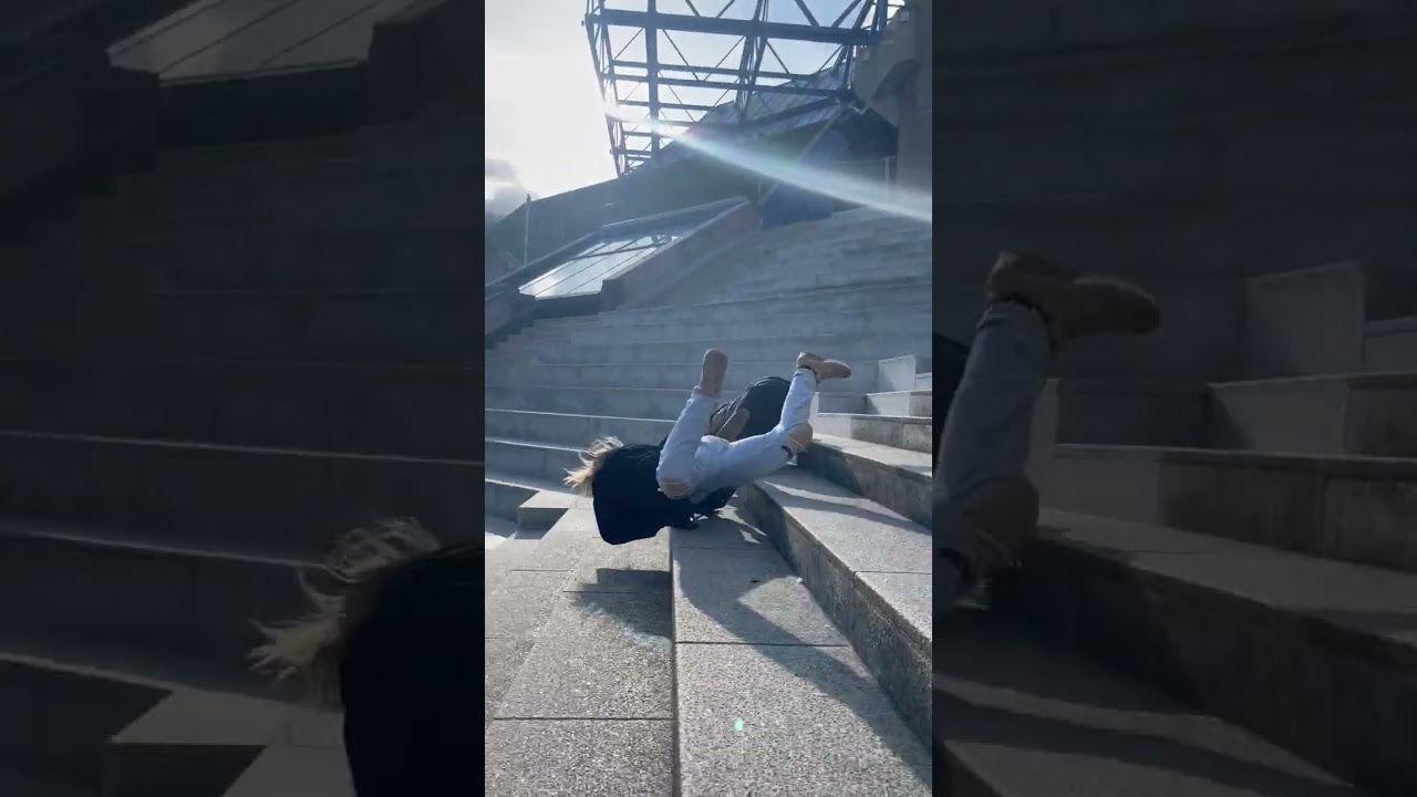 Girls run down stairs in stadium then one trips and they both falls forward and rolls down steps