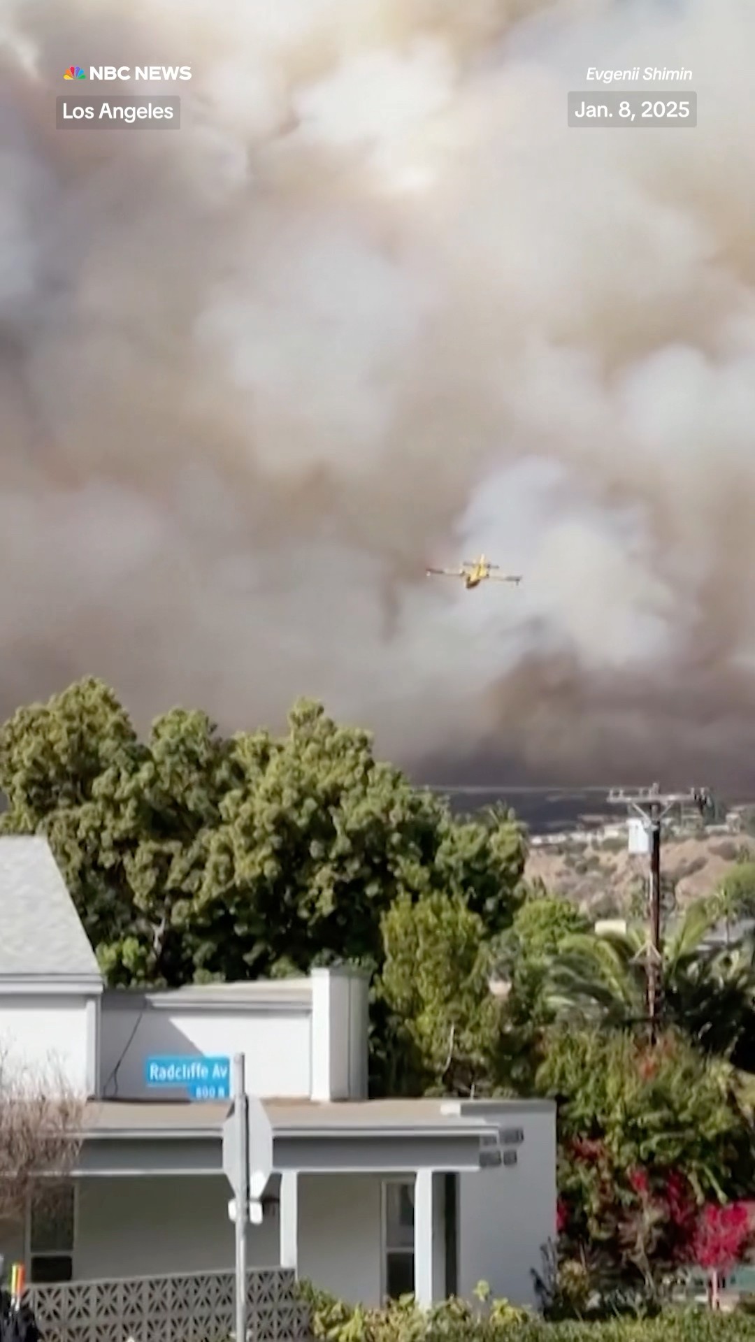 A firefighting plane flies into smoke to help contain fast-moving wildfires in the Los Angeles area.