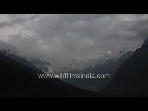 Sunlight breaks through clouds over the snow-covered peaks of Pithoragarh
