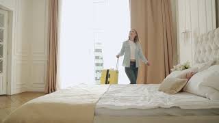 woman walking into a hotel room with suitcase and  E437LMX