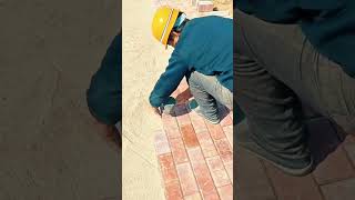 Installing rectangular paving bricks on a flat sand surface using a rubber mallet to ensure