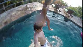 Young Happy Couple Jumping In Resort Swimming Pool During Amazing Sunset And Splashing Droplets
