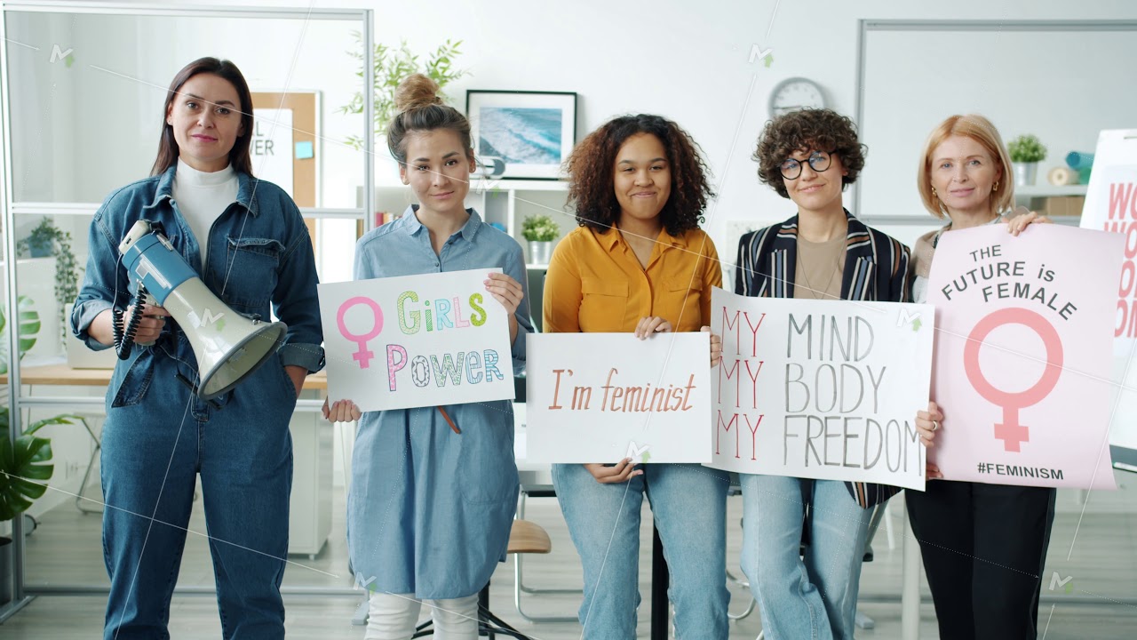 Slow motion portrait of women feminists standing indoors holding banners and loudspeaker